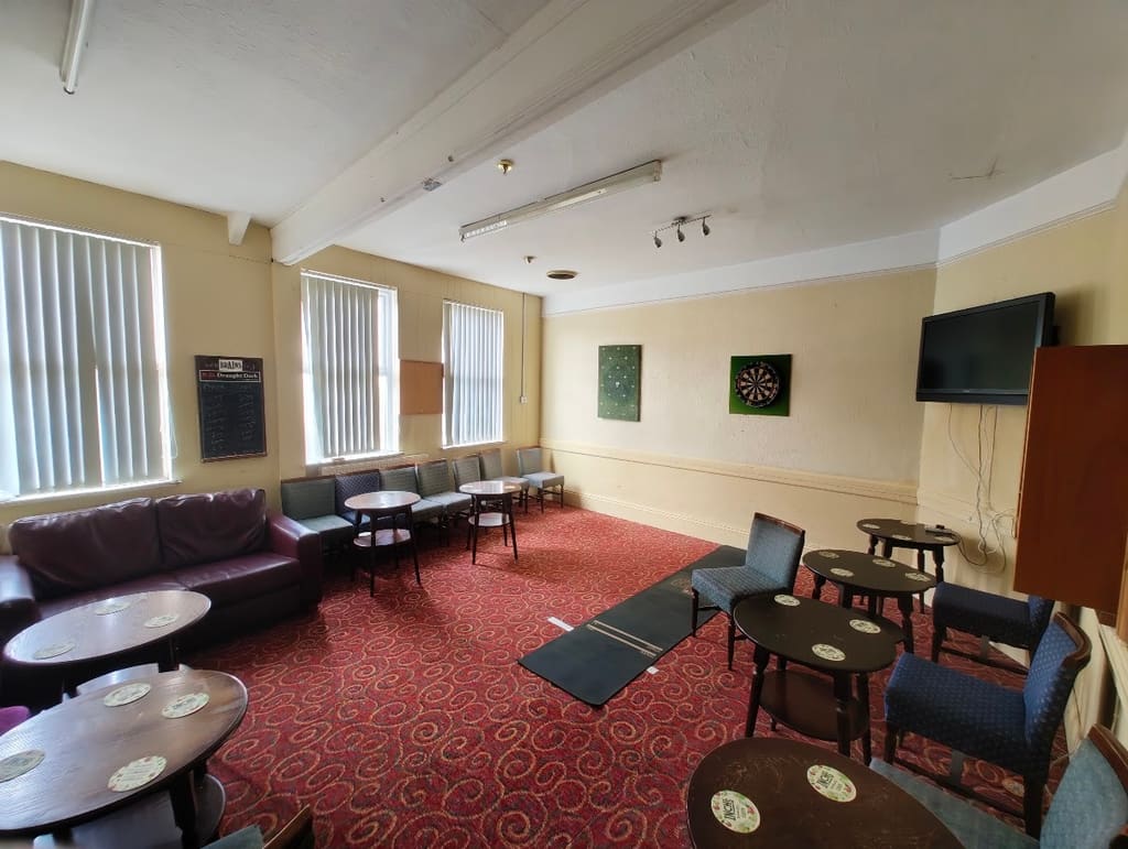 The darts room, two boards on the wall with an oche mat on the floor and seating around the edge