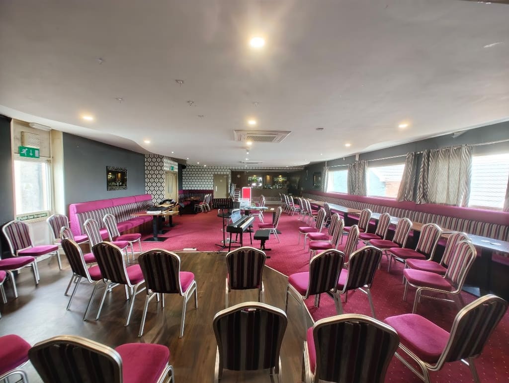 The function room set out with chairs and tables, the stage end at the far wall