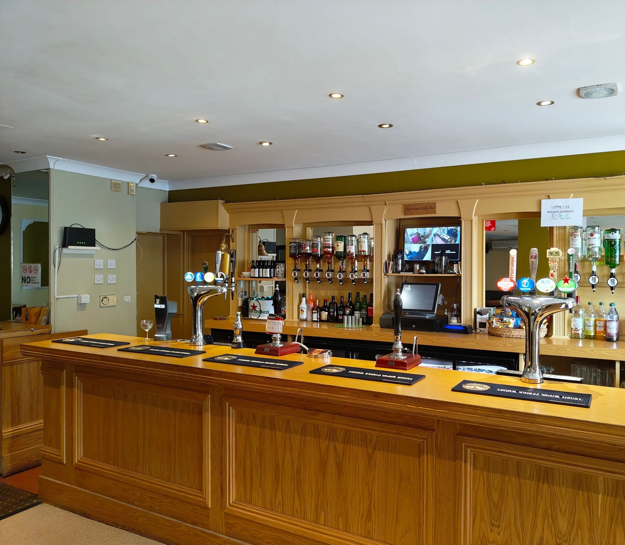 The members’ bar, a long wooden bar with several draught pumps and a mirrored back wall